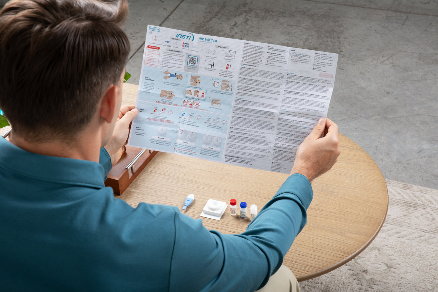 Man reading INSTI HIV self-test instructions for use with complete rapid test kit on table