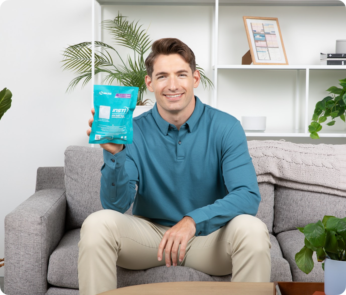 INSTI HIV Self Test kit packaging showing results in 1 minute, held by smiling man at home
