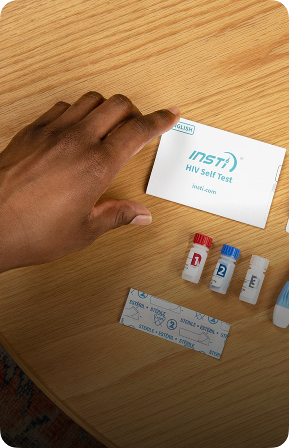 INSTI HIV Self Test kit contents including reagent bottles, lancet, and instructions on table
