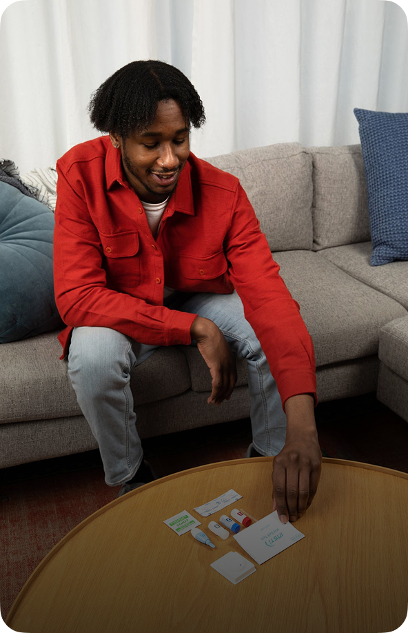 Man arranging INSTI HIV home test kit components on coffee table before self-testin