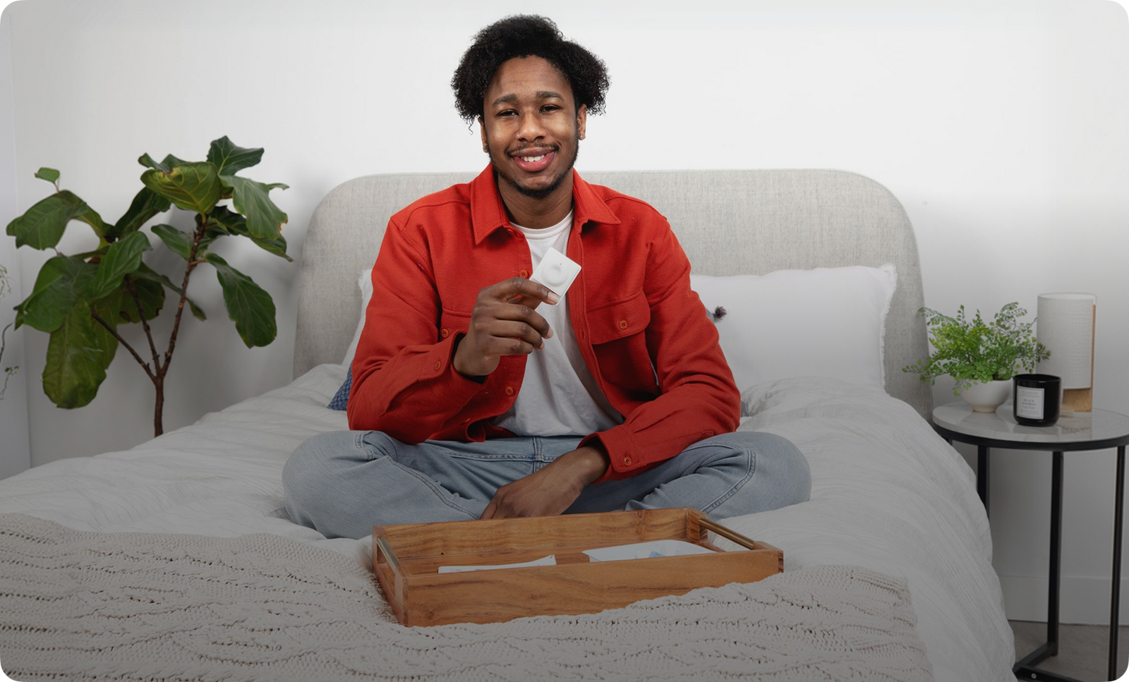 Man sitting on bed holding INSTI HIV self-test device after completing home HIV test